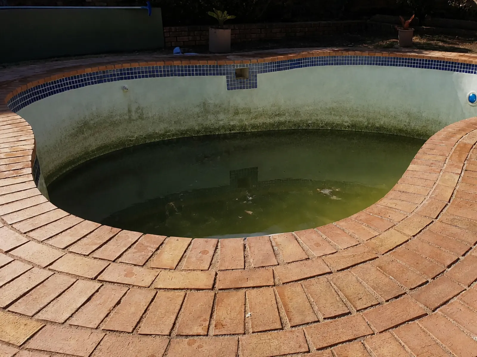 Neglected fibreglass swimming pool before repairs