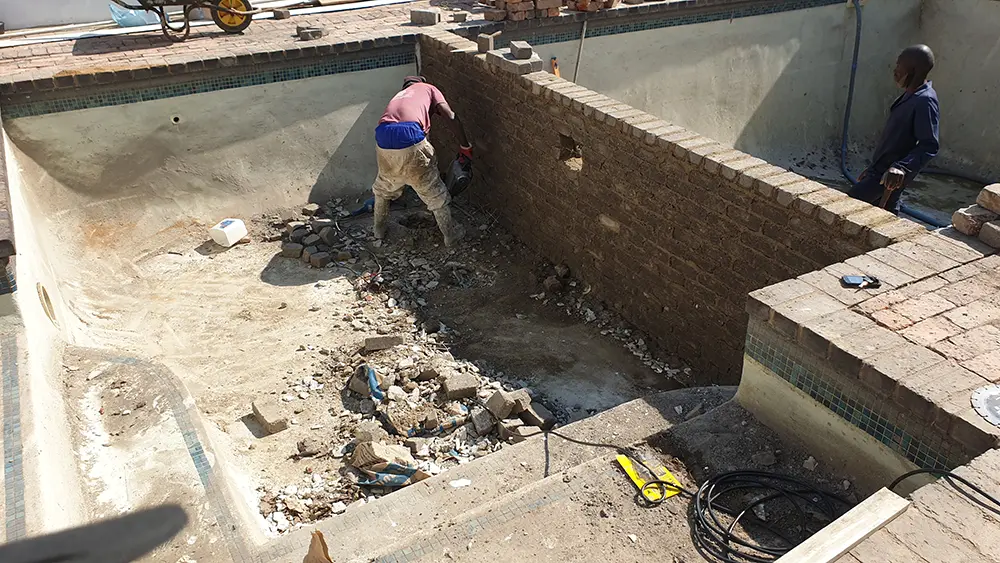 Construction work inside an existing swimming pool during pool resizing